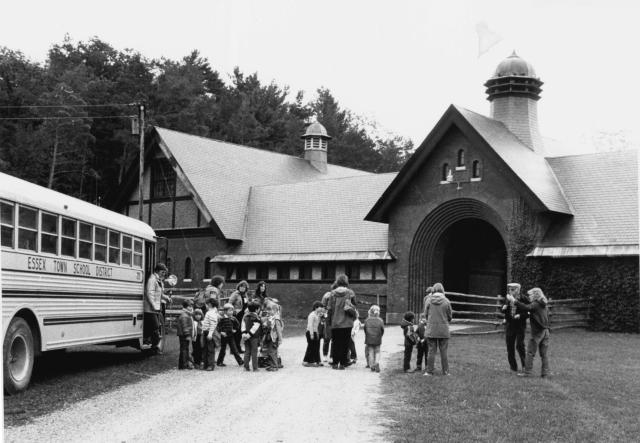 black and white photo of students stepping off a schoolbus arriving at the Coach Barn