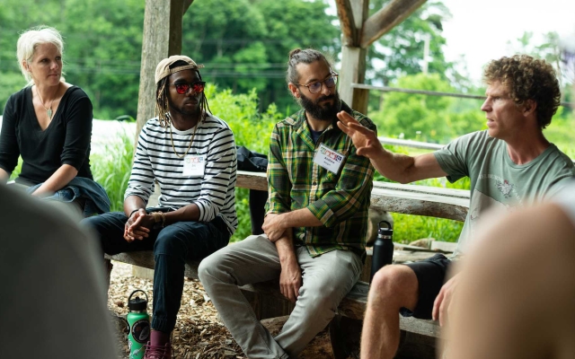 Educators sit under an outdoor pavilion in a garden