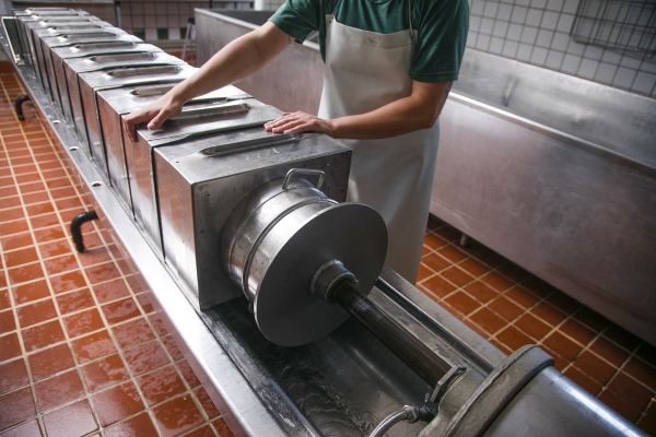 A worker operates a large press, which applies pressure to a row of hoops.