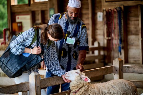 Man in Taqiyah and women patting a sheep in a pen