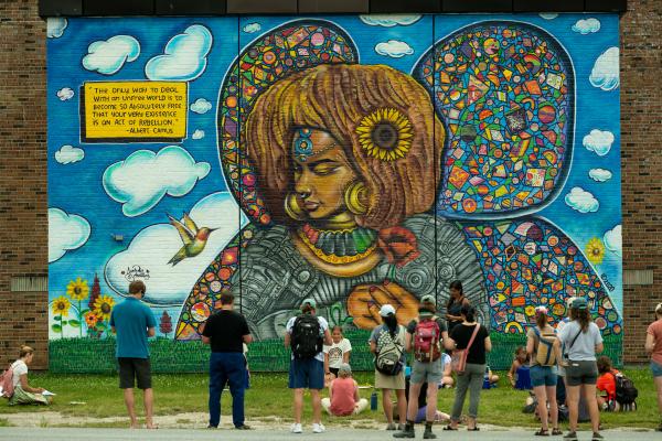Workshop participants stand in front of a mural at a Burlington elementary school