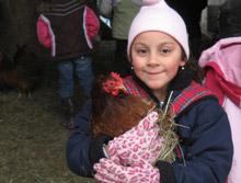 A smiling child holding a chicken